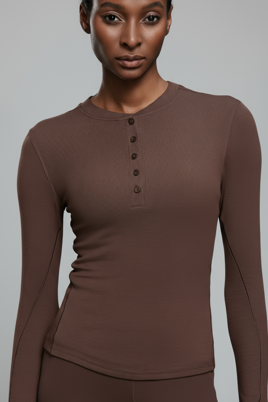 Woman wearing a brown long-sleeve top with buttons on a white background