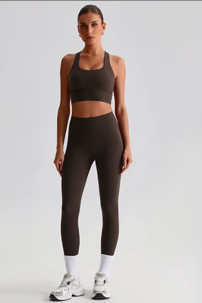 Woman wearing a brown sports bra and leggings set on a white background